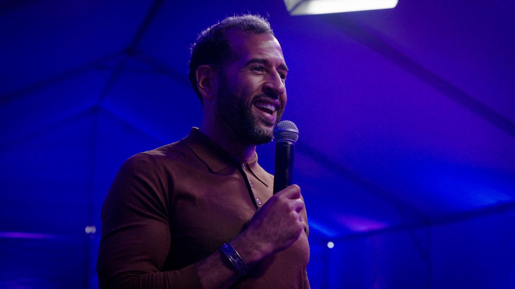 Ian Cain on stage with a microphone, smiling
